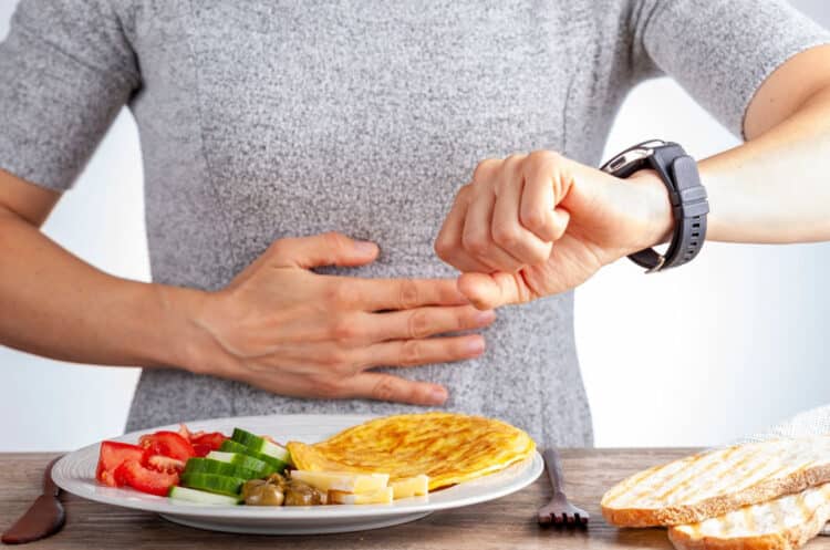 a person with a watch on her hand looking at a plate of food