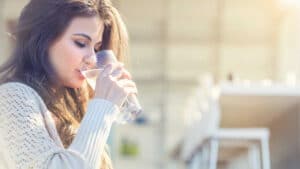 a woman drinking water from a glass