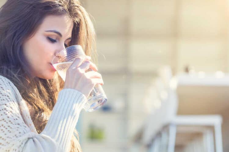 a woman drinking water from a glass